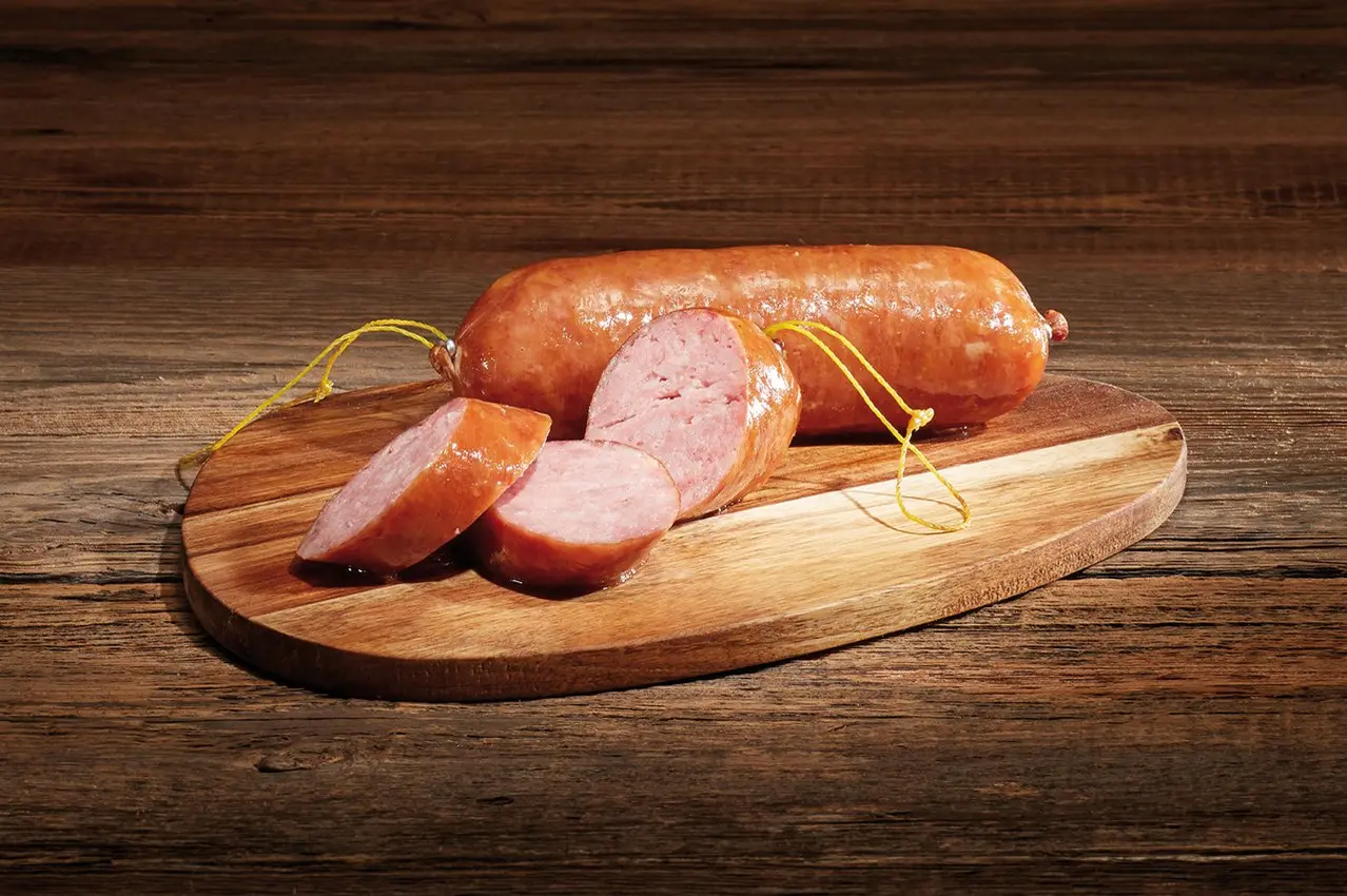 Saucisson neuchâtelois IGP entier et tranché sur une planche